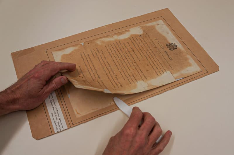 Removing document from backing to begin conservation